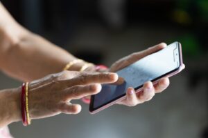 Female with wrinkled hands using a smartphone with a blurry background