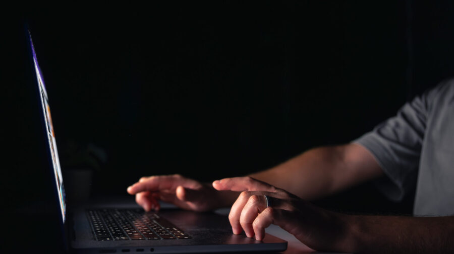 Young man works at the computer at night.