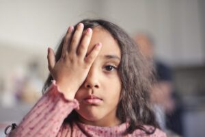 little girl covers one eye with her hand