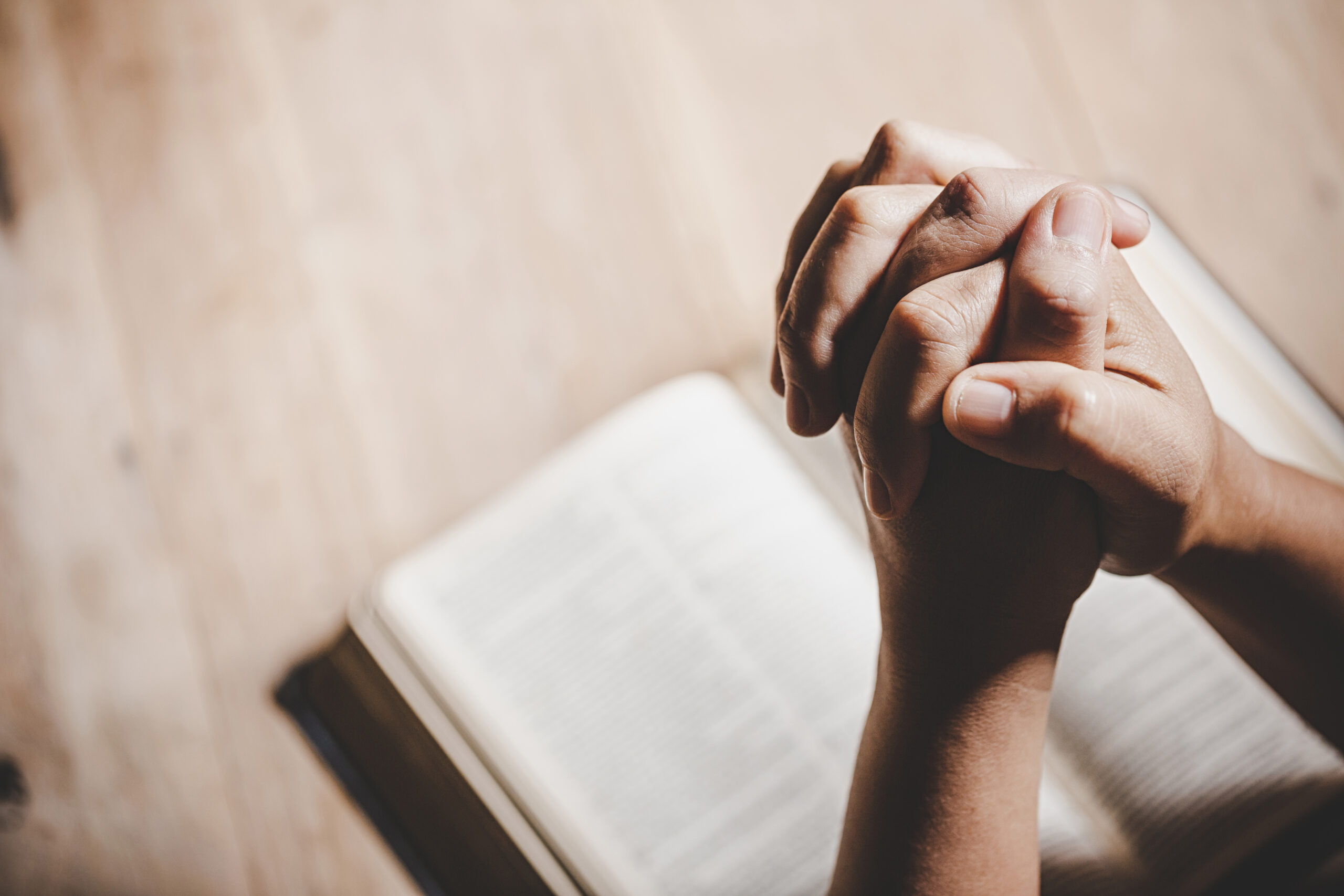 Spirituality and religion, Hands folded in prayer on a Holy Bibl