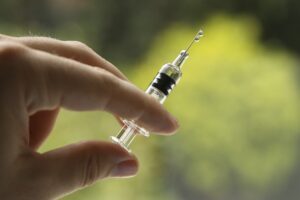 A closeup shot of a female holding a syringe, on a blurred background