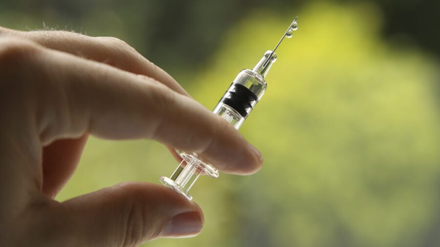 A closeup shot of a female holding a syringe, on a blurred background