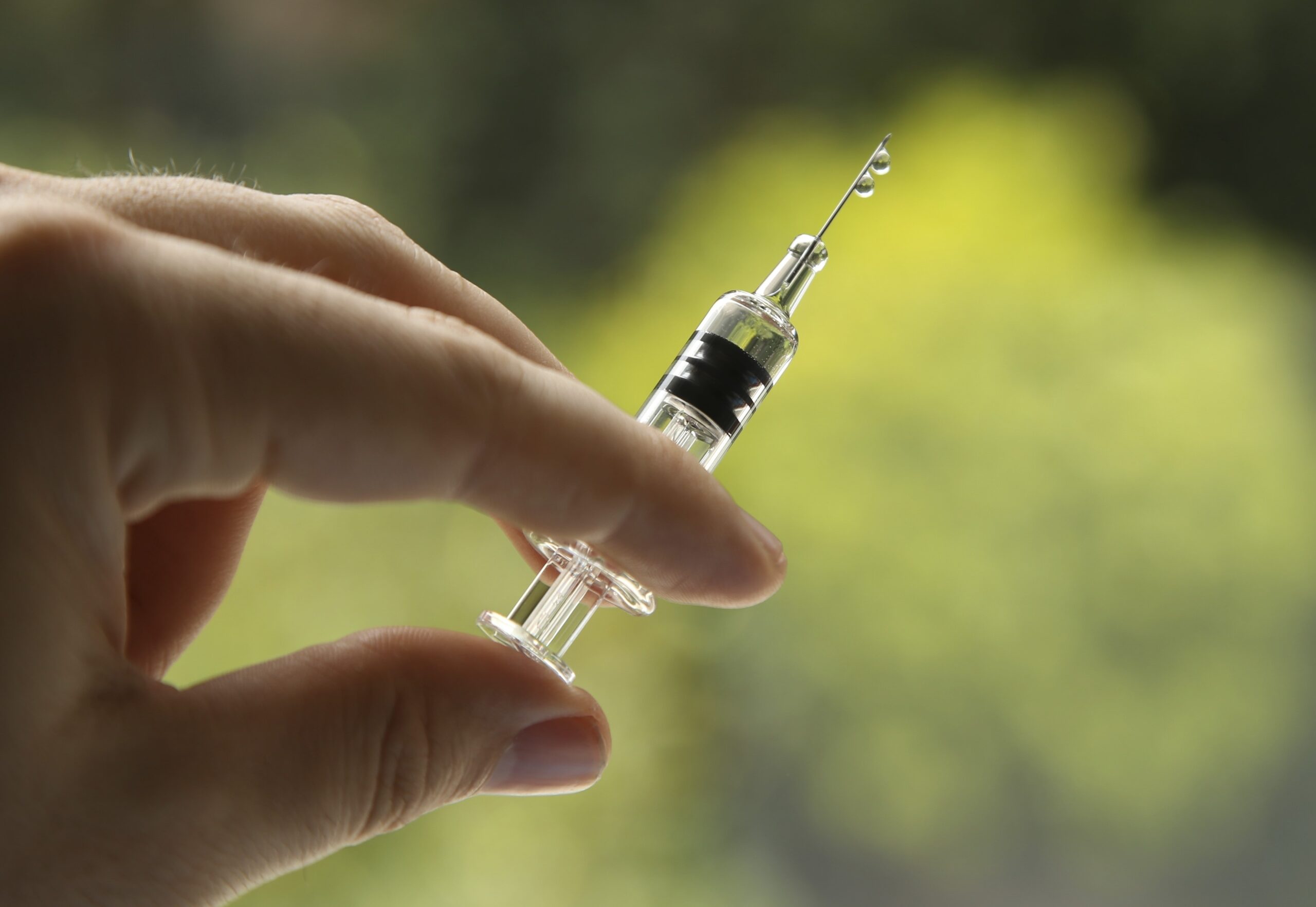 A closeup shot of a female holding a syringe, on a blurred background