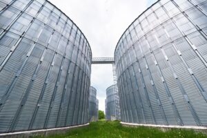 Agricultural Silos. Building Exterior. Storage and drying of grains, wheat, corn, soy, sunflower against the blue sky with white clouds