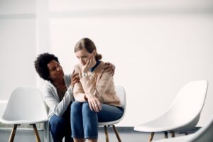 Caring African American woman consoling sad woman before group t