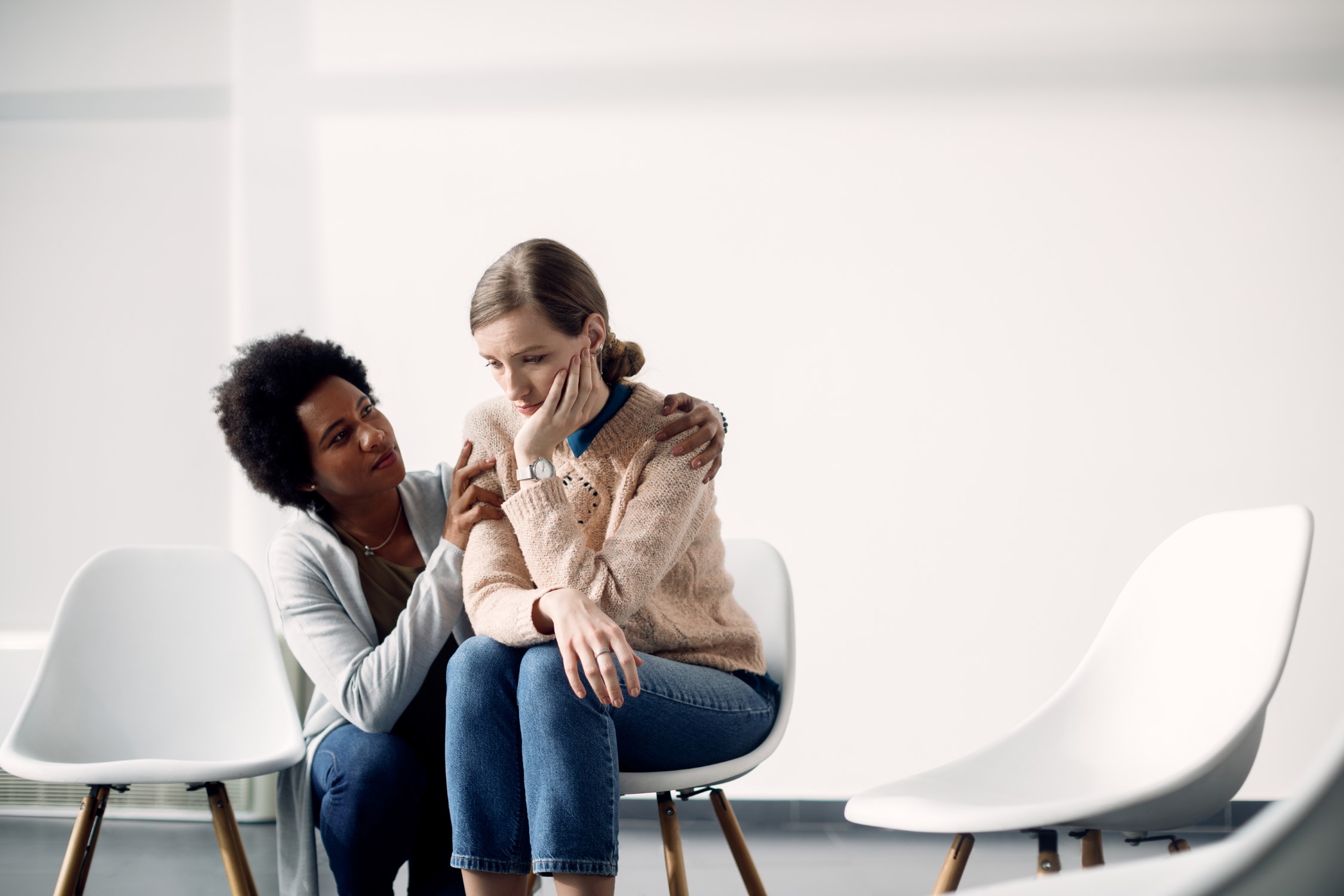 Caring African American woman consoling sad woman before group t